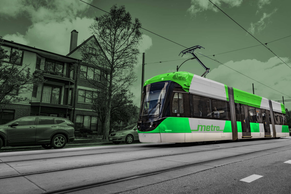 3D rendering of a street-level MetroLink train, stylized in green including a green MetroLink vehicle.