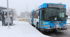 Photo of a MetroBus next to a snow covered sidewalk and bus stop